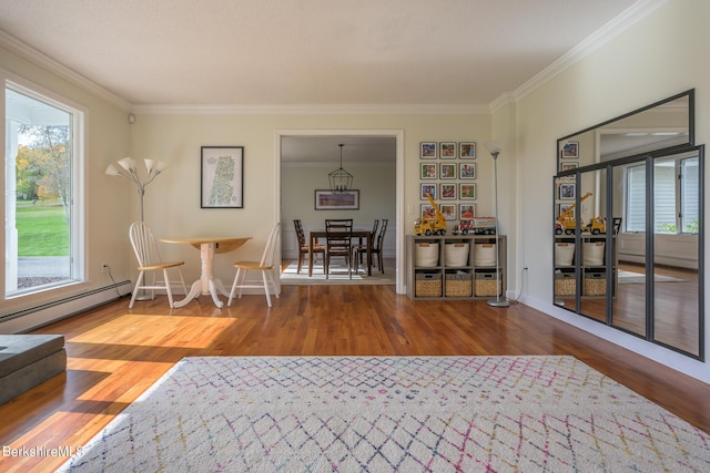 living area with hardwood / wood-style flooring, plenty of natural light, baseboard heating, and crown molding