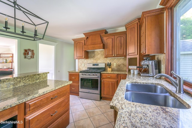 kitchen featuring gas stove, light stone countertops, sink, and custom range hood