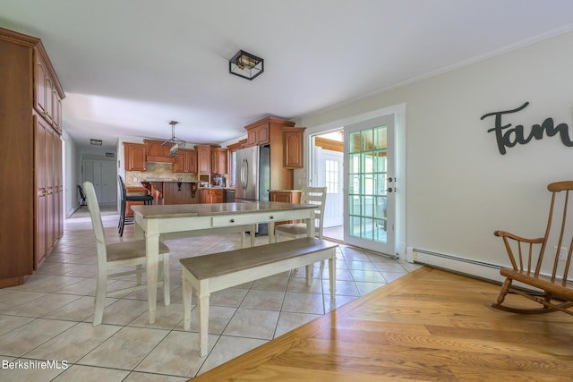 tiled dining room featuring crown molding and a baseboard heating unit