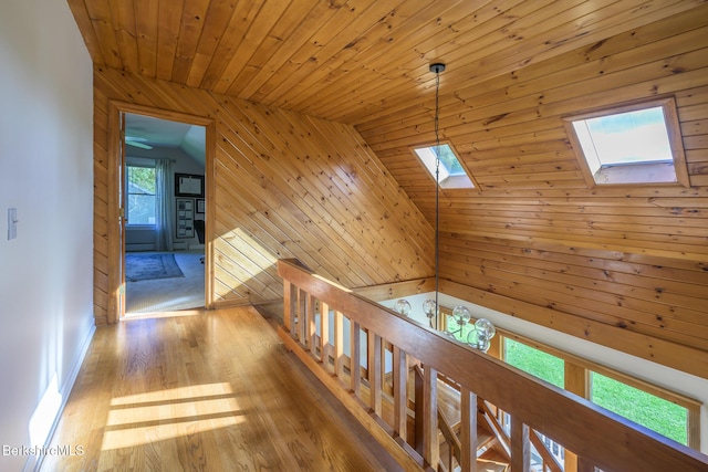 corridor featuring lofted ceiling with skylight, wooden walls, wooden ceiling, and wood-type flooring