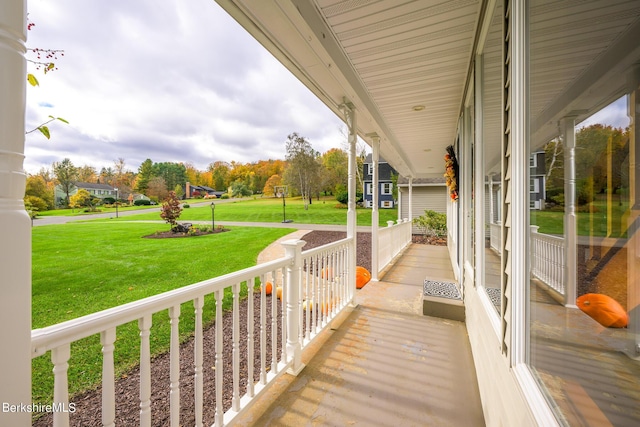 wooden deck with a lawn and covered porch