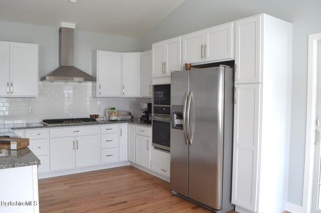 kitchen featuring white cabinets, wall chimney range hood, and appliances with stainless steel finishes