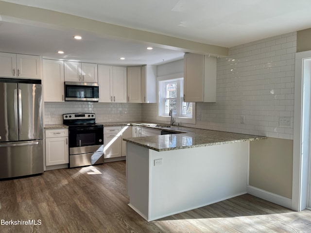 kitchen with tasteful backsplash, light stone countertops, dark wood-style flooring, and appliances with stainless steel finishes