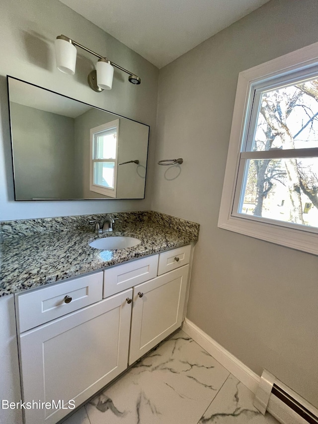 bathroom with a baseboard heating unit, baseboards, marble finish floor, and vanity