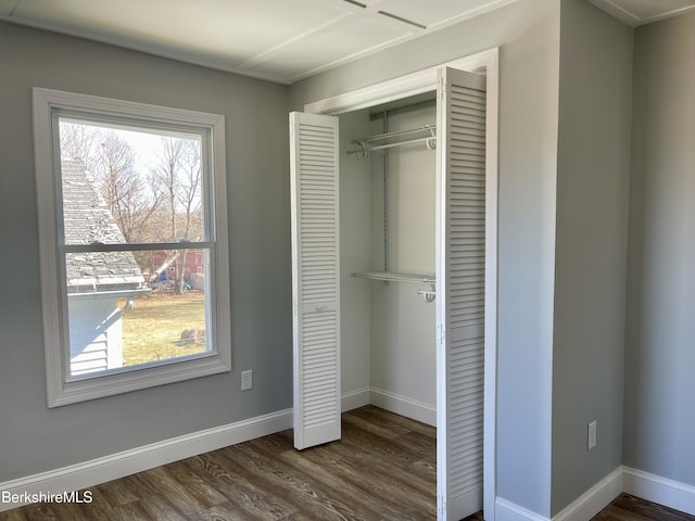 unfurnished bedroom featuring a closet, baseboards, and dark wood-style flooring