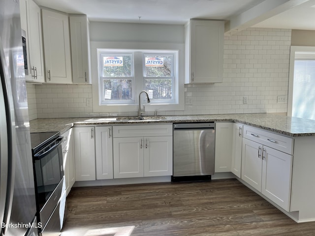 kitchen featuring dark wood-type flooring, a sink, appliances with stainless steel finishes, white cabinets, and a peninsula