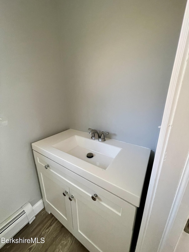 bathroom featuring a baseboard heating unit, vanity, and wood finished floors