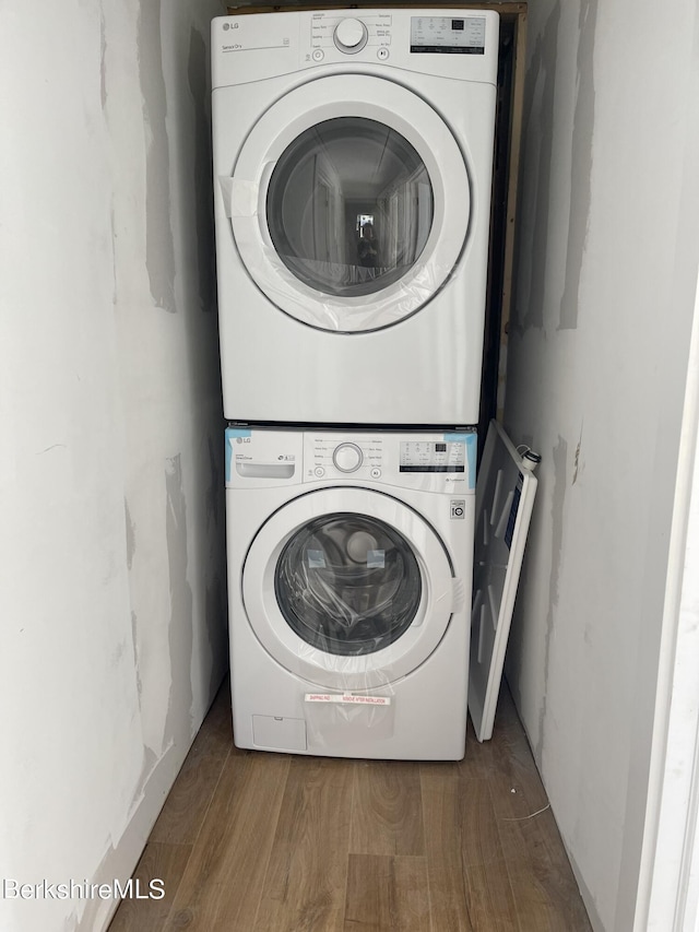 washroom with laundry area, wood finished floors, and stacked washer and clothes dryer