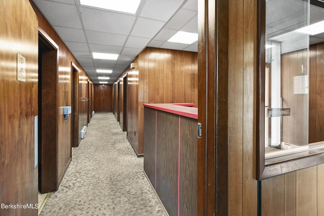 hall with a paneled ceiling and wooden walls