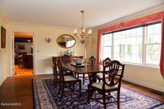 dining room with crown molding, hardwood / wood-style floors, and an inviting chandelier