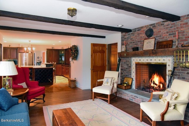 living room with an inviting chandelier, beamed ceiling, dark wood-type flooring, and a brick fireplace