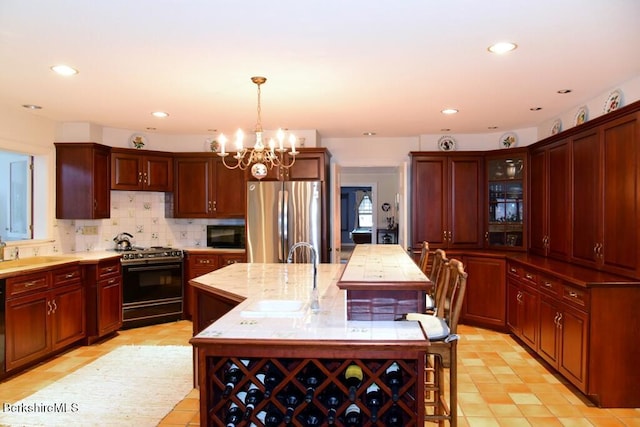 kitchen with stainless steel refrigerator, backsplash, an island with sink, decorative light fixtures, and range