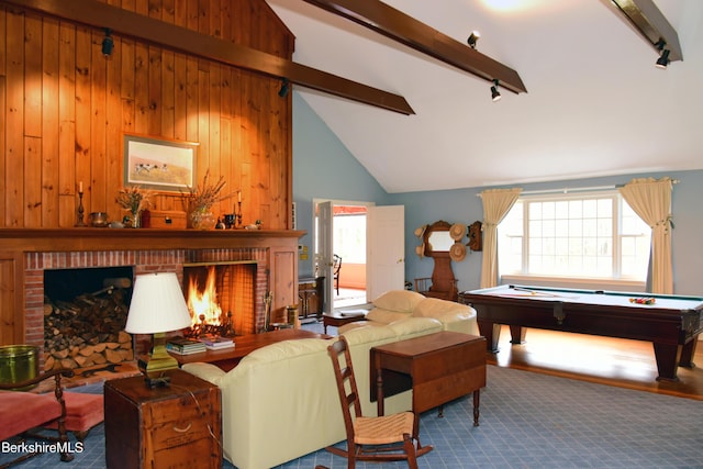 living room with wooden walls, billiards, beamed ceiling, and a brick fireplace