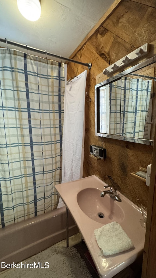 bathroom with a sink and shower / tub combo with curtain
