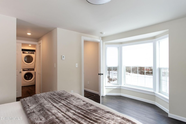 unfurnished bedroom with dark hardwood / wood-style flooring and stacked washer and dryer