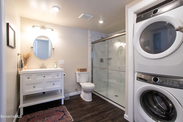 bathroom featuring stacked washer and dryer, vanity, hardwood / wood-style flooring, toilet, and a shower with door