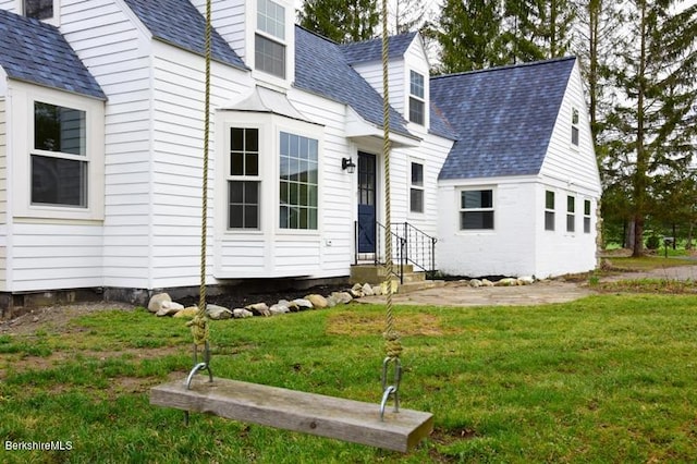 view of front of home featuring a shingled roof and a front lawn