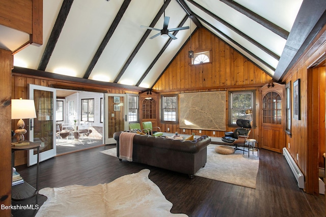 living room with a healthy amount of sunlight, beam ceiling, wooden walls, and a baseboard radiator