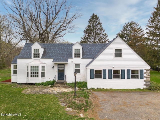 view of front of house featuring roof with shingles, a front yard, and entry steps