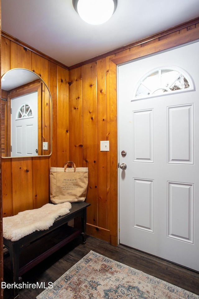 foyer entrance featuring wooden walls and dark hardwood / wood-style floors