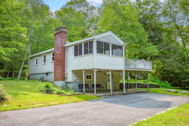 49 Bryant Rd, Otis, MA 01253 - view of front of house with a sunroom, a patio, a chimney, and a front yard