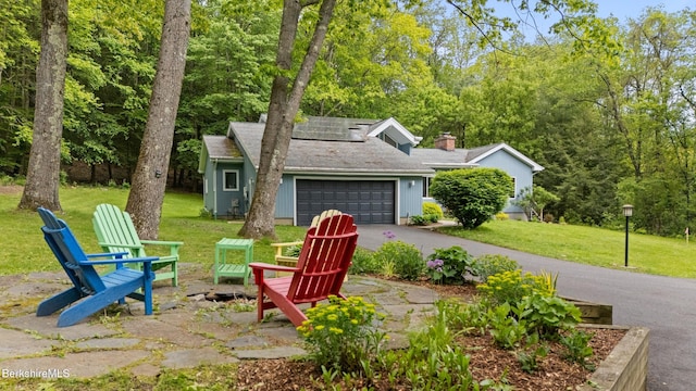 505 Kirchner Rd, Dalton, MA 01226 - view of front of property featuring a garage, driveway, a front lawn, roof mounted solar panels, and a chimney