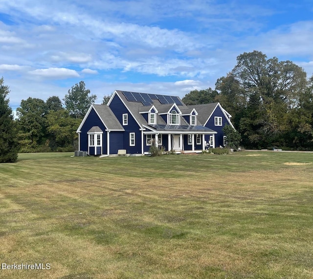 view of front of home with a front yard, solar panels, and covered porch