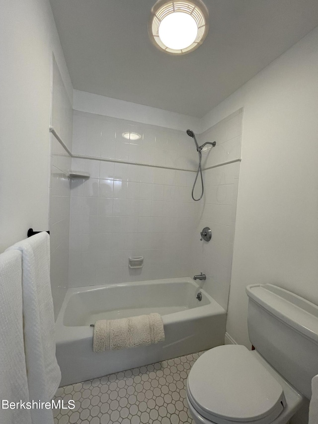 bathroom with tile patterned flooring, tiled shower / bath combo, and toilet