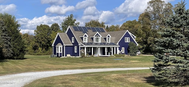 view of front facade featuring a porch, cooling unit, a front yard, and solar panels