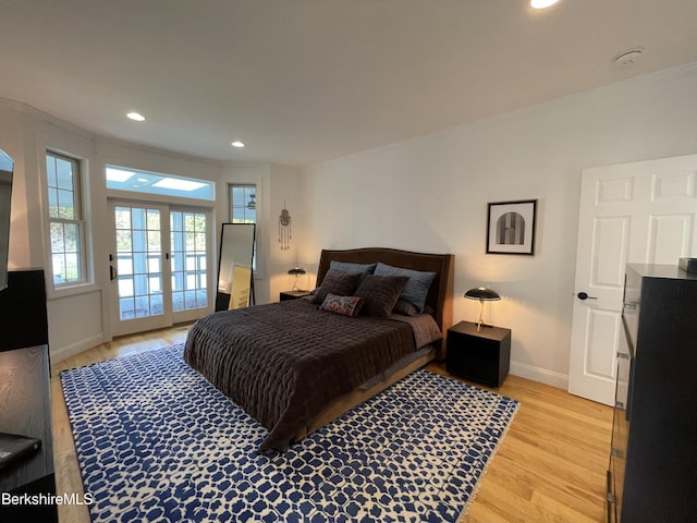 bedroom featuring light hardwood / wood-style floors, ornamental molding, access to outside, and french doors