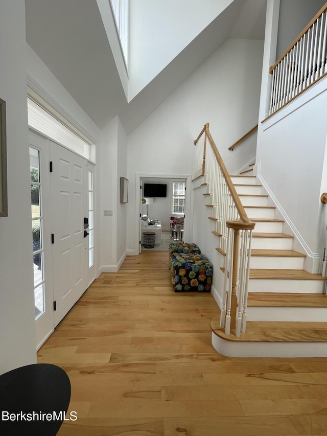 foyer entrance featuring a towering ceiling and light wood-type flooring