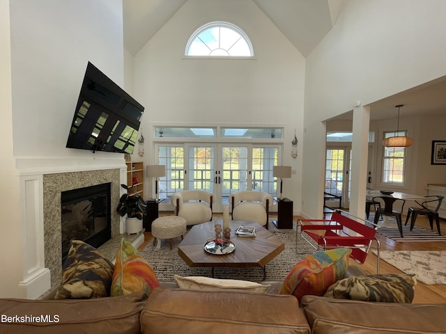 living room featuring a high end fireplace, french doors, hardwood / wood-style floors, and a high ceiling