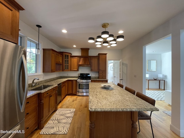 kitchen featuring a breakfast bar, appliances with stainless steel finishes, decorative light fixtures, and sink