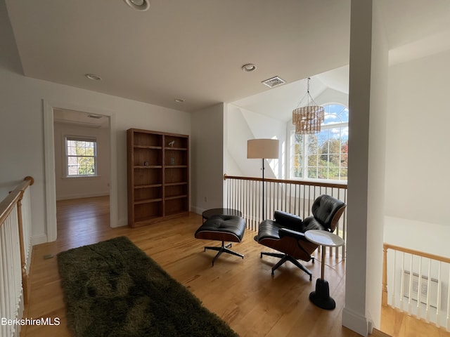 sitting room featuring a notable chandelier, light wood-type flooring, and lofted ceiling