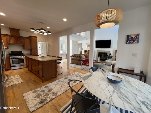 kitchen featuring a center island, stainless steel appliances, light stone counters, pendant lighting, and light hardwood / wood-style floors