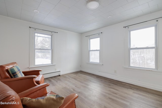 sitting room with a baseboard heating unit, a wealth of natural light, and light hardwood / wood-style flooring