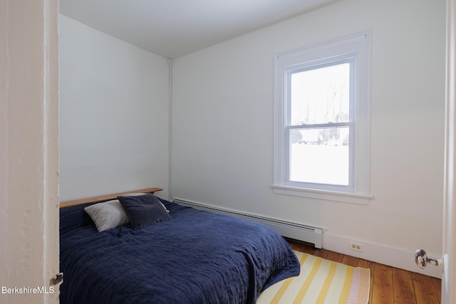 bedroom with wood-type flooring and a baseboard heating unit