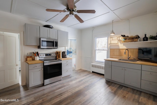 kitchen with radiator heating unit, sink, stainless steel appliances, pendant lighting, and gray cabinets