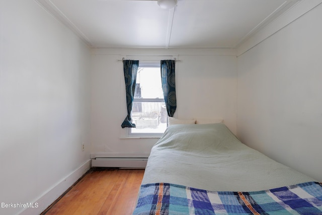 bedroom with hardwood / wood-style flooring, crown molding, and baseboard heating