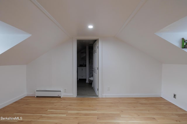 additional living space with lofted ceiling, light hardwood / wood-style flooring, and a baseboard radiator