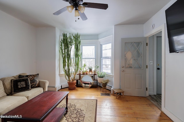 living room featuring ceiling fan, light hardwood / wood-style floors, and a baseboard heating unit