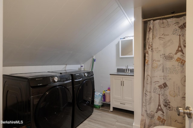 washroom featuring light wood-type flooring, washer and clothes dryer, and sink