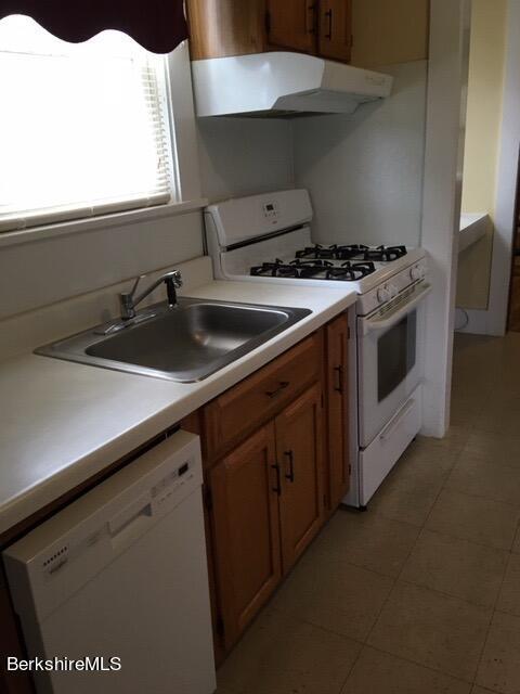 kitchen with sink, white appliances, and exhaust hood