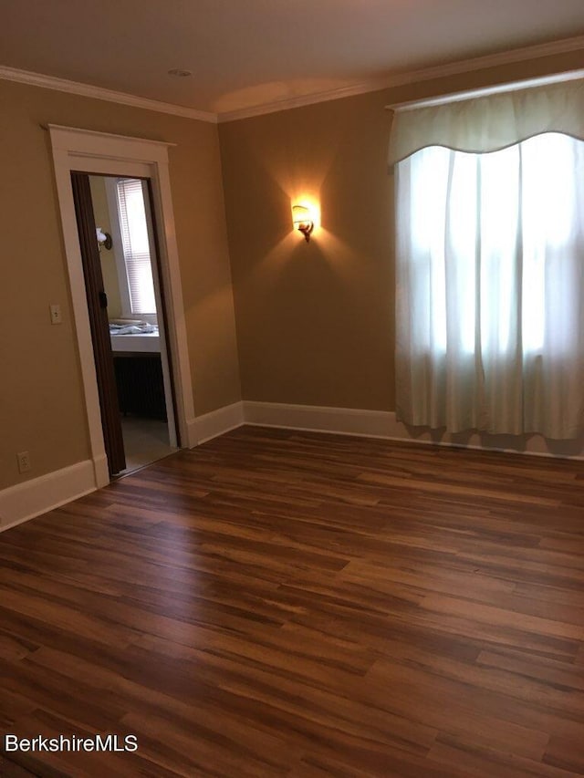 empty room featuring dark hardwood / wood-style flooring, crown molding, and plenty of natural light