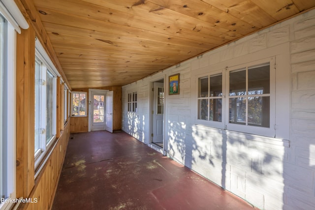 unfurnished sunroom featuring wood ceiling and concrete flooring