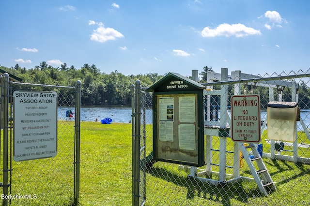 view of playground featuring a water view, fence, and a yard