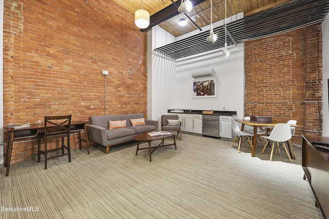 carpeted living room featuring a towering ceiling, brick wall, and wooden ceiling