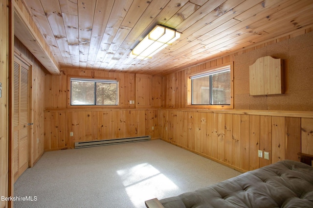 spare room featuring a baseboard heating unit, wooden ceiling, light carpet, and wood walls