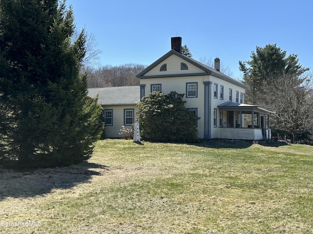 rear view of property with a chimney, a lawn, and a sunroom