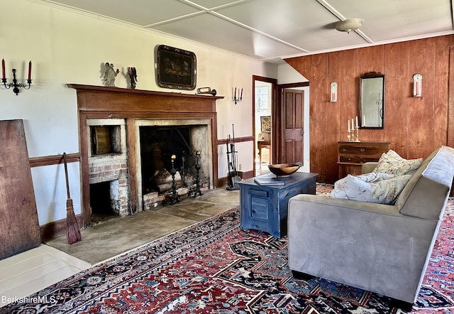 living room with ornamental molding, a fireplace, and wooden walls